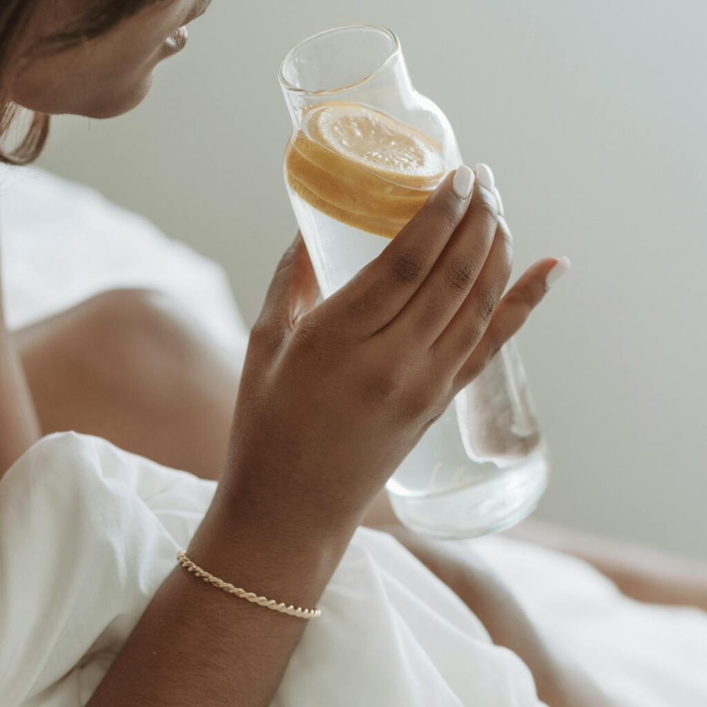 Young woman holding a glass bottle of detox water with fresh fruits